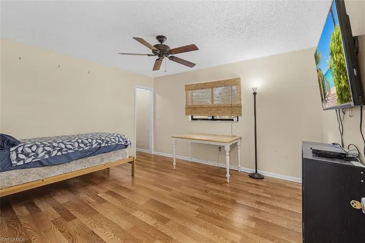 Bedroom featuring a textured ceiling, wood-type flooring, and ceiling fan