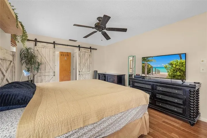 Bedroom featuring ceiling fan, hardwood / wood-style flooring, and a barn door