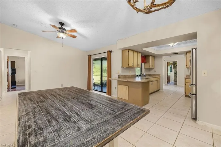 Kitchen with light tile patterned flooring, a textured ceiling, ceiling fan, vaulted ceiling, and sink