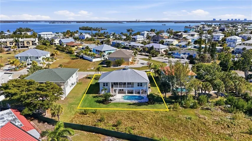 Aerial perspective of suburban area with a nearby body of water and property parcel outlined - Virtually Edited