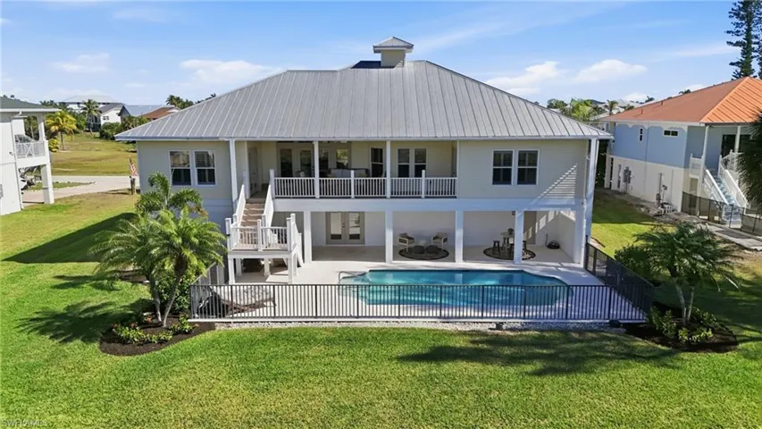 Back of house featuring stairway, a patio area, a metal roof, and a balcony - Virtually Edited