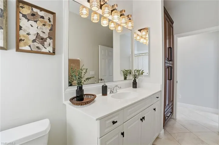 Bathroom with vanity, a chandelier, and light tile patterned floors - Virtually Edited