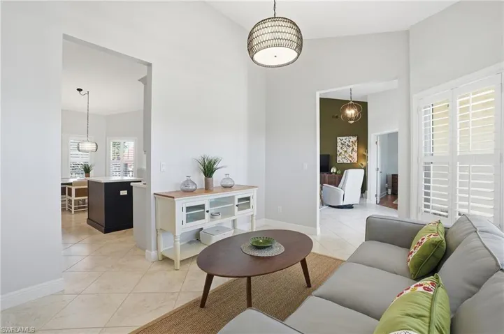Living room featuring light tile patterned floors, high vaulted ceiling, and a chandelier - Virtually Edited
