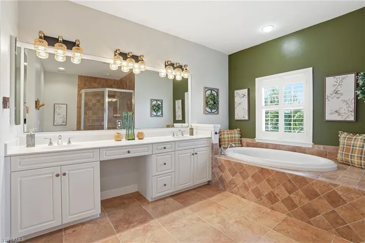 Bathroom featuring a stall shower, double vanity, and a bath - Virtually Edited