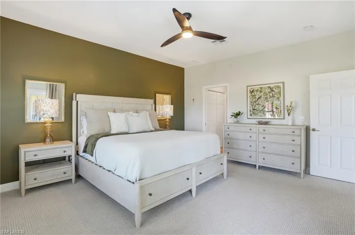 Bedroom featuring light colored carpet, a ceiling fan, and a closet - Virtually Edited