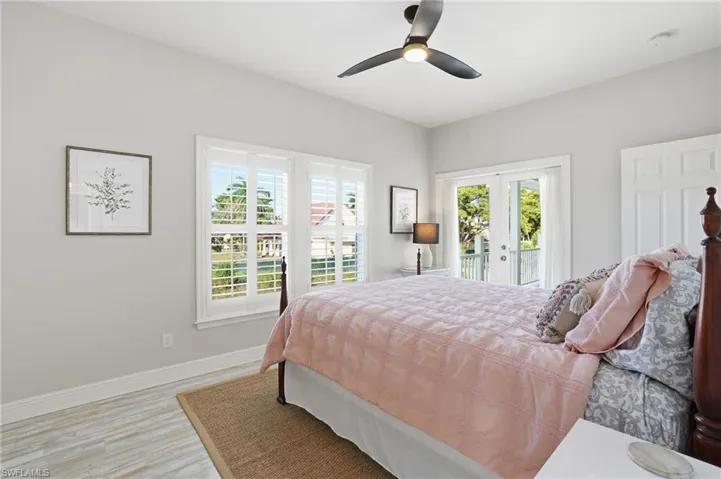 Bedroom with french doors, a ceiling fan, access to exterior, and light wood-style floors - Virtually Edited