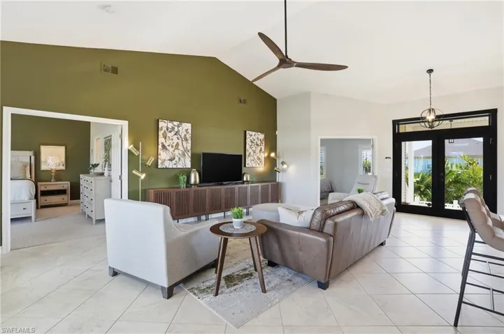 Living room featuring french doors, ceiling fan, and high vaulted ceiling -Virtually Edited