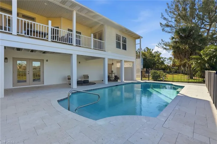 View of pool with a patio area, french doors, and a balcony - Virtually Edited