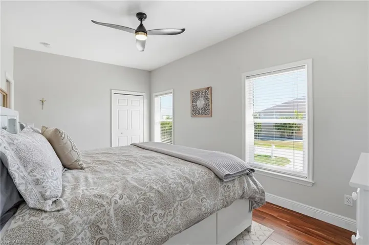 Bedroom with a ceiling fan, dark wood-style floors, and a closet - Virtually Edited