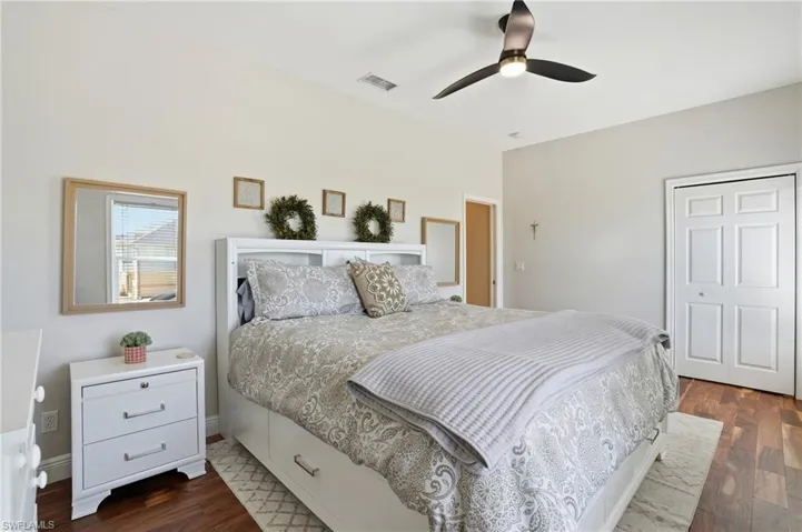 Bedroom with a closet, dark wood-style flooring, and ceiling fan - Virtually Edited