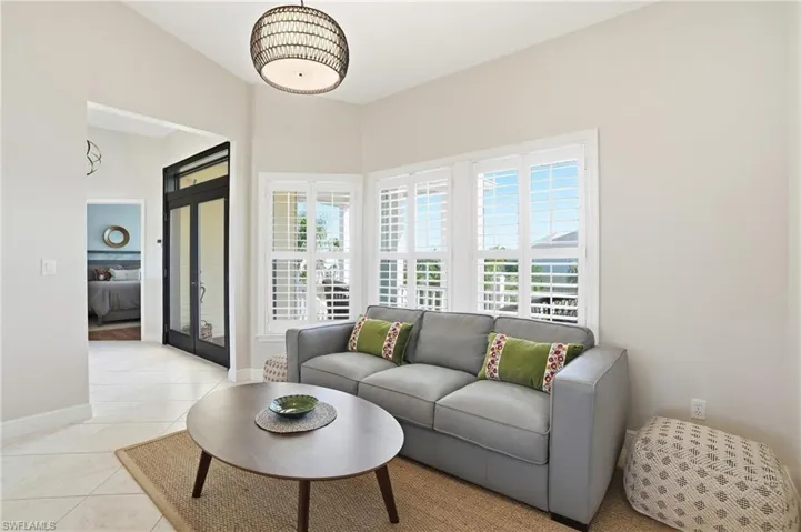 Living area with light tile patterned flooring and baseboards - Virtually Edited