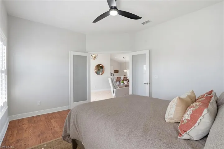 Bedroom featuring a ceiling fan, light wood finished floors, and vaulted ceiling - Virtually Edited