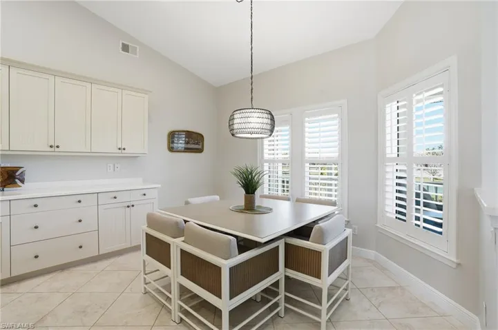Dining space with vaulted ceiling and light tile patterned floors - Virtually Edited