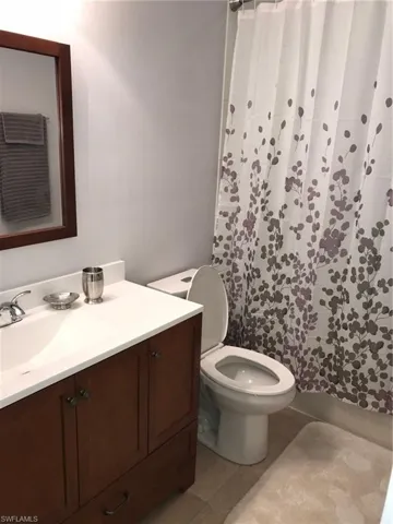 Full bath featuring vanity, a shower with shower curtain, and light tile patterned floors