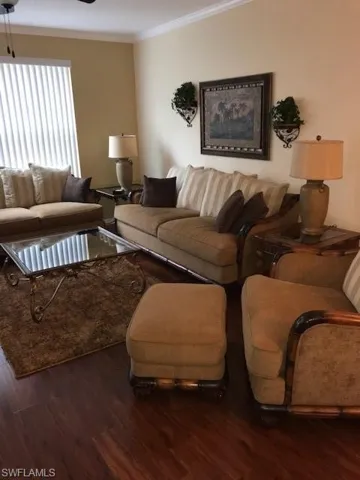 Living area featuring dark wood-type flooring, ornamental molding, and a ceiling fan