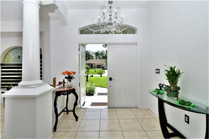 Tiled foyer entrance with an inviting chandelier and ornate columns