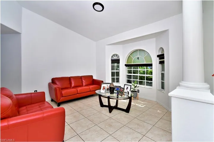 Living room with vaulted ceiling, ornate columns, and light tile patterned floors