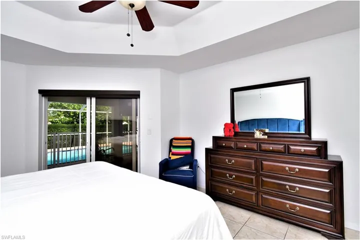 Tiled bedroom featuring a raised ceiling, access to outside, and ceiling fan