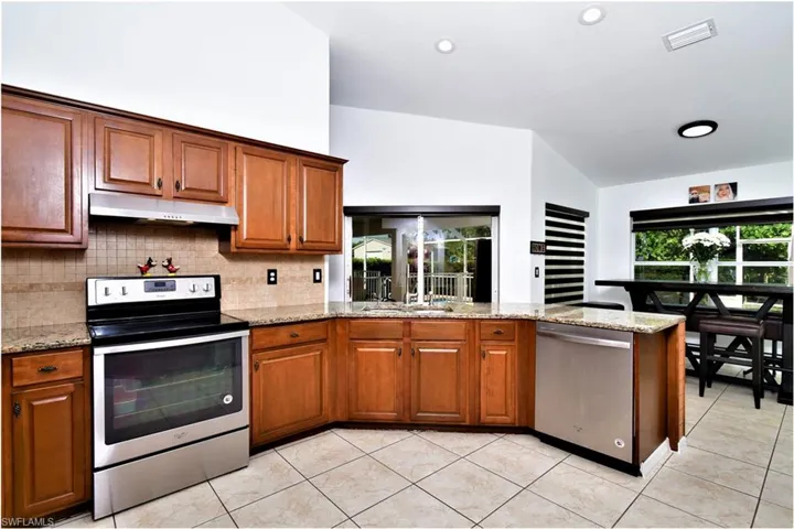 Kitchen featuring light stone counters, sink, appliances with stainless steel finishes, and light tile patterned flooring
