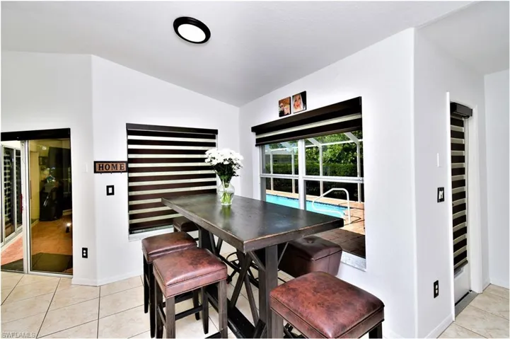 Tiled dining area featuring vaulted ceiling