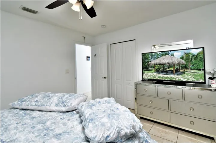 Bedroom with a closet, ceiling fan, and light tile patterned floors