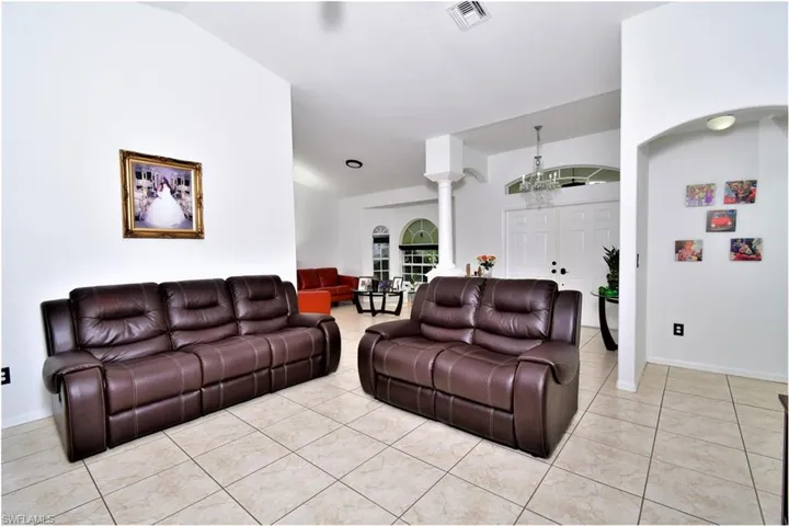 Living room with a notable chandelier, lofted ceiling, and light tile patterned flooring