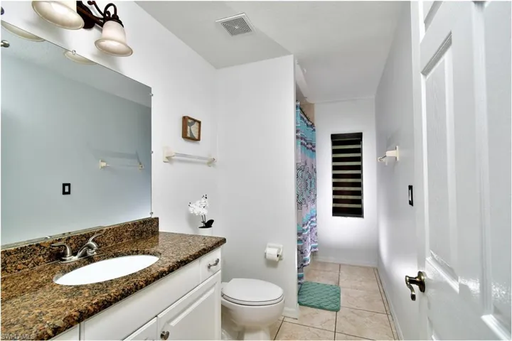 Bathroom featuring tile patterned flooring, toilet, and vanity