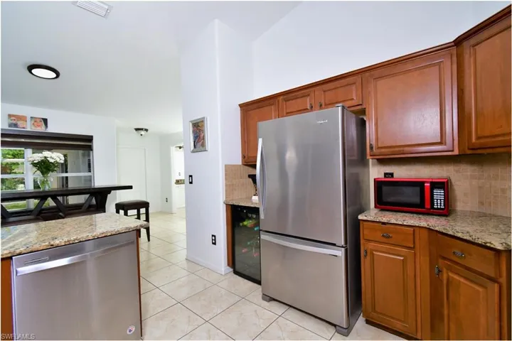 Kitchen with light tile patterned floors, appliances with stainless steel finishes, light stone counters, and backsplash