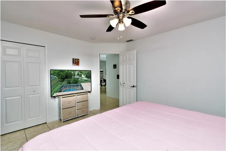 Tiled bedroom featuring ceiling fan and a closet