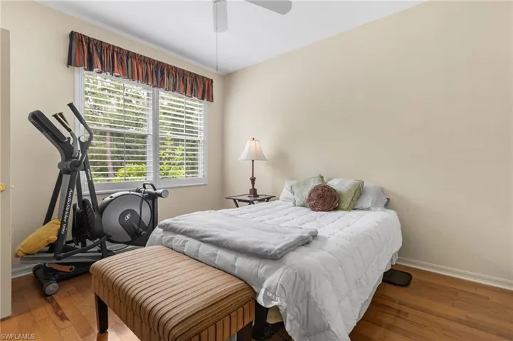 Bedroom with hardwood / wood-style floors, a ceiling fan, and baseboards