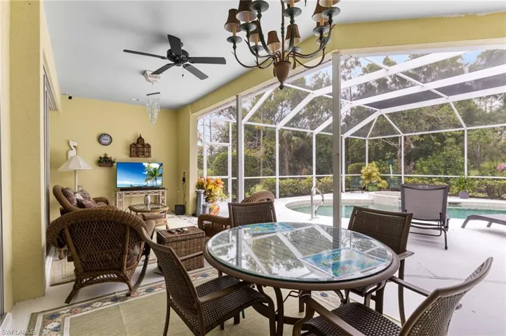 View of patio featuring a lanai, outdoor dining space, an outdoor pool, and a ceiling fan
