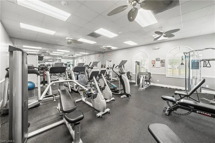 Exercise room with a paneled ceiling, baseboards, and ceiling fan
