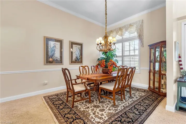 Dining area featuring carpet floors, a chandelier, ornamental molding, and baseboards