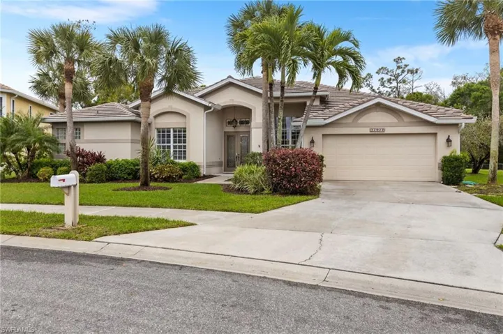 View of front facade with stucco siding, french doors, concrete driveway, an attached garage, and a front yard