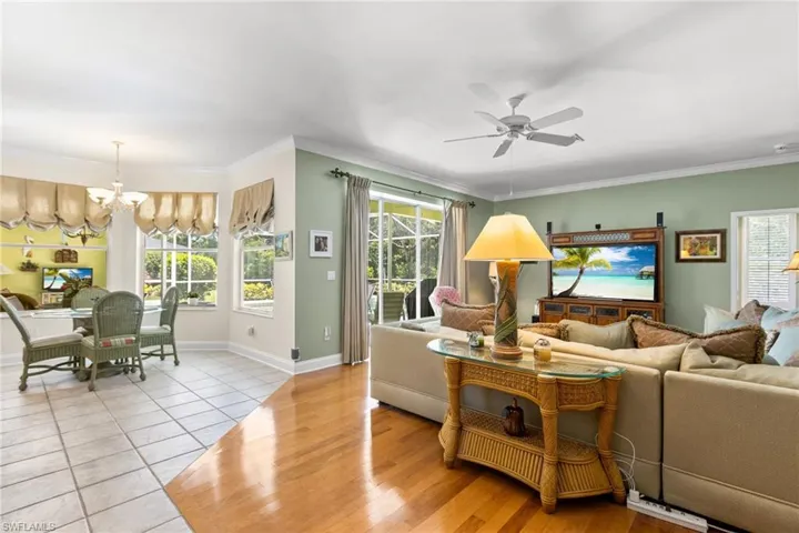 Tiled living area with a chandelier, ceiling fan, healthy amount of natural light, baseboards, and ornamental molding