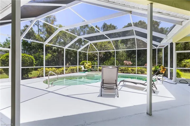 View of pool with a patio area, a pool with connected hot tub, and glass enclosure