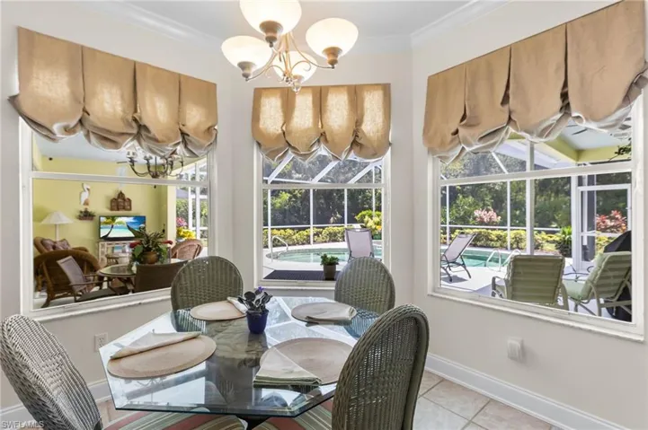 Dining space with a chandelier, light tile patterned flooring, baseboards, and ornamental molding