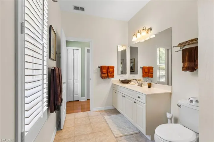 Bathroom with toilet, vanity, tile patterned floors, and baseboards