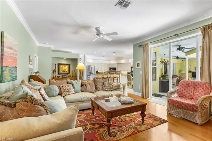 Living room featuring a ceiling fan, light wood-style floors, and ornamental molding