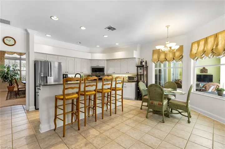 Kitchen featuring stainless steel appliances, a chandelier, ornamental molding, light tile patterned floors, and a center island