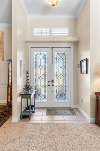 Tiled foyer entrance featuring crown molding, baseboards, and french doors