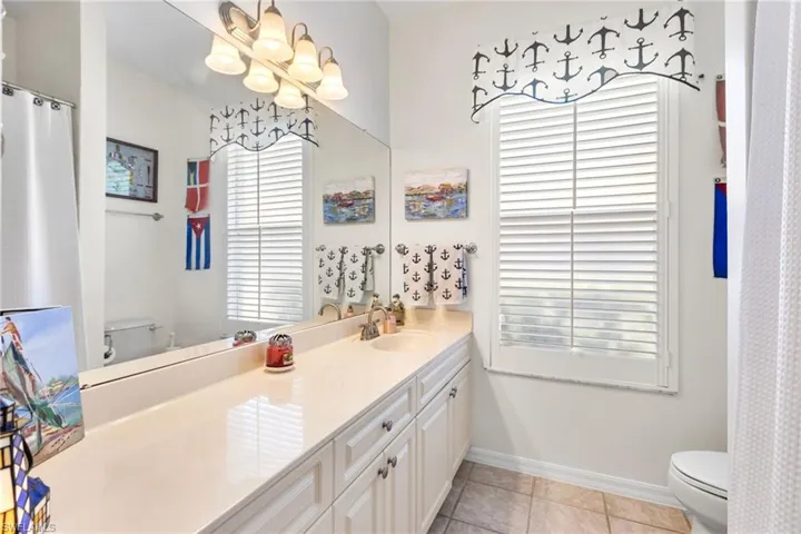 Bathroom featuring toilet, a chandelier, tile patterned floors, baseboards, and vanity