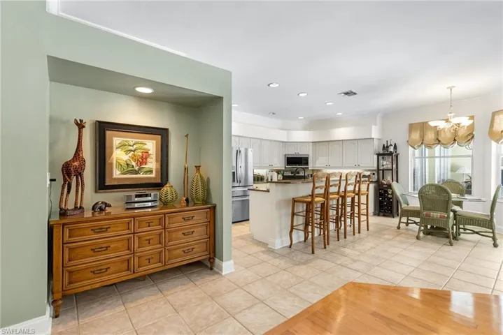 Kitchen featuring appliances with stainless steel finishes, a chandelier, light tile patterned floors, a kitchen breakfast bar, and crown molding