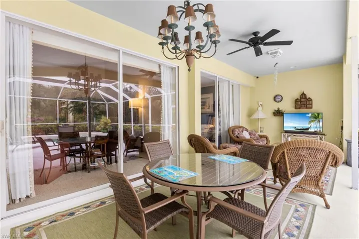 Dining room with ceiling fan with notable chandelier and a sunroom