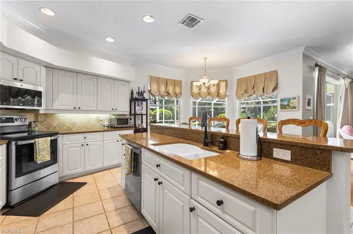 Kitchen featuring appliances with stainless steel finishes, a sink, healthy amount of natural light, ornamental molding, and tasteful backsplash