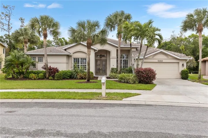 View of front of house with a front yard, driveway, an attached garage, stucco siding, and a tile roof