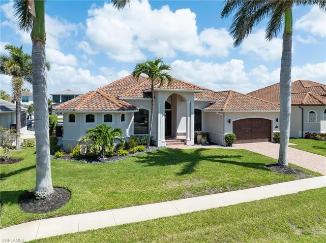Mediterranean / spanish home with a tile roof, a front yard, decorative driveway, and an attached garage