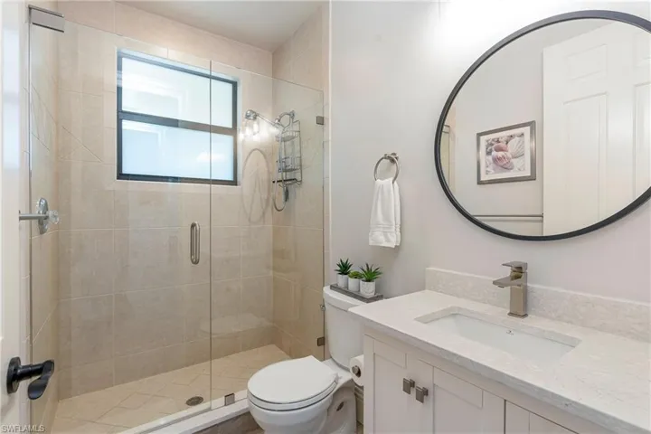 Full bathroom with toilet, vanity, and a stall shower