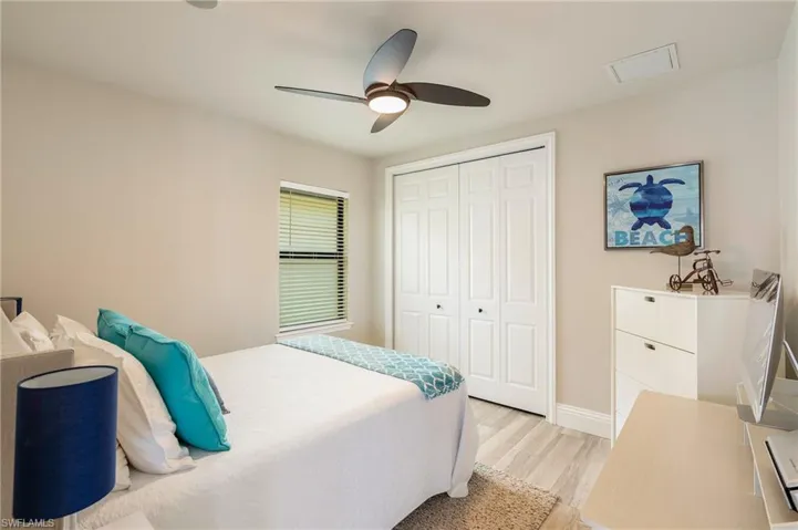 Bedroom with baseboards, light wood-style floors, visible vents, a ceiling fan, and a closet