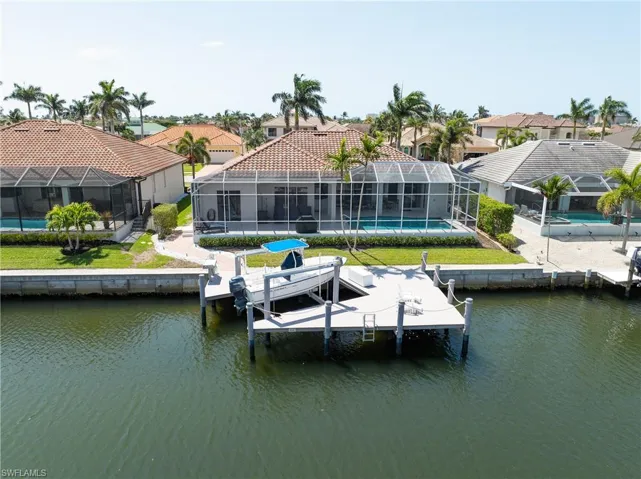 View of dock featuring a water view, a lanai, an outdoor pool, boat lift, and a residential view